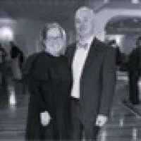 women and older man in the front lawn trees behind them