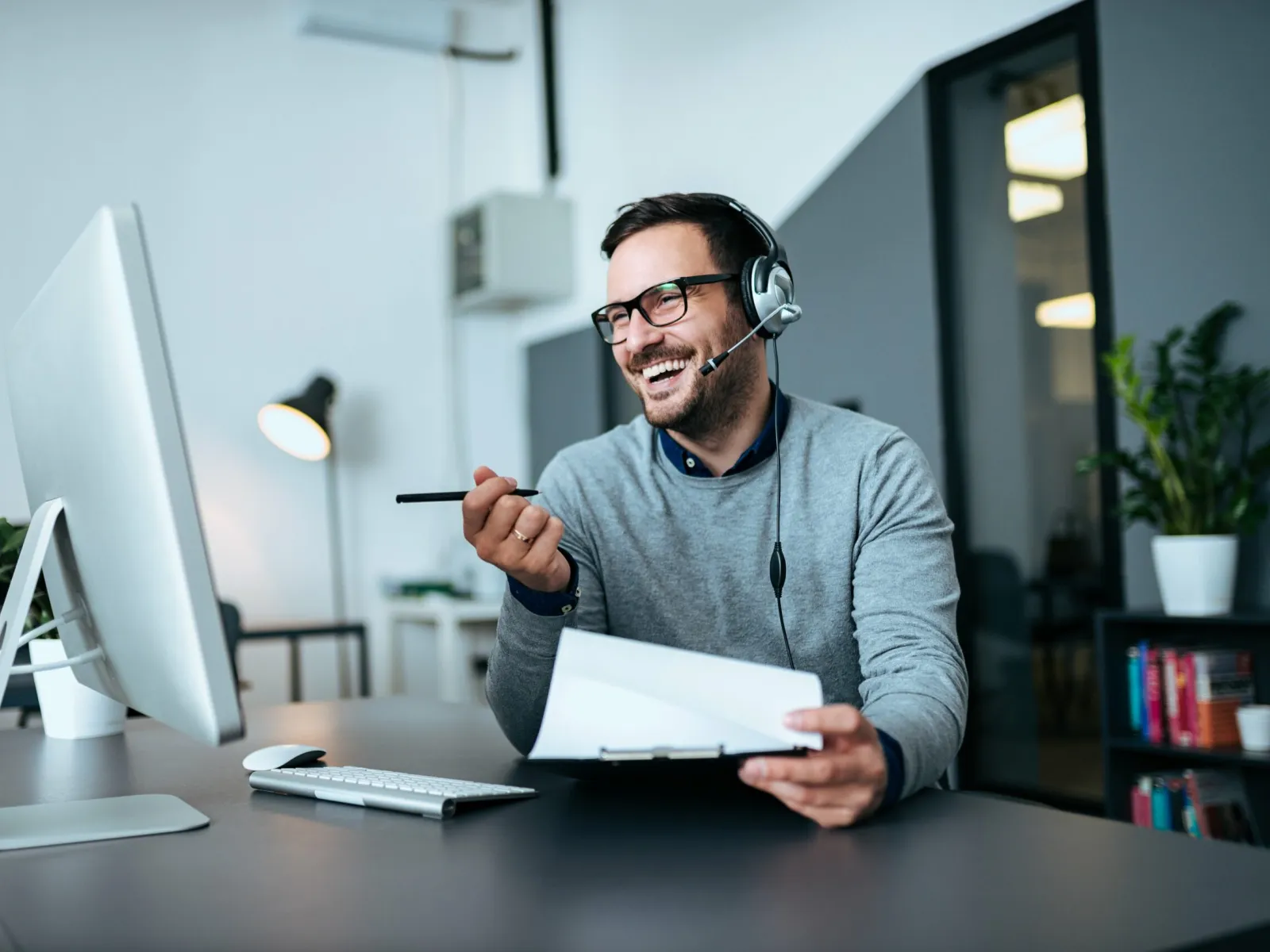 a man wearing headphones and holding a pen and a paper